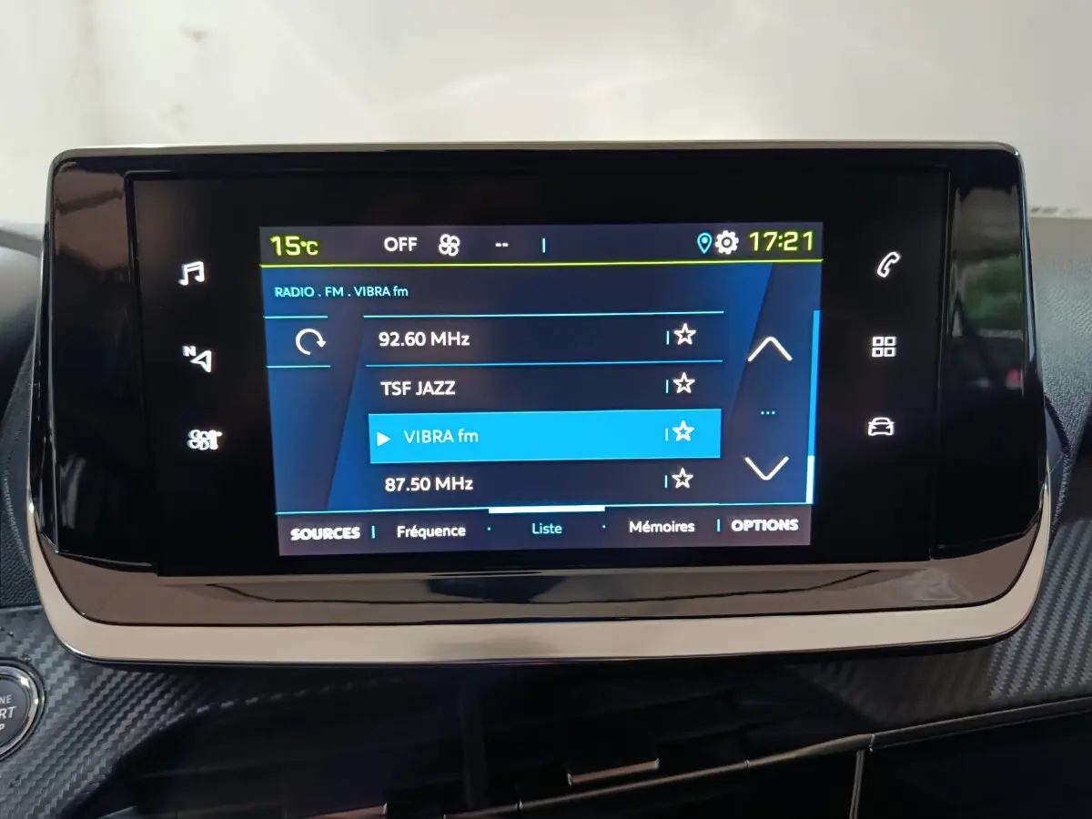Écran tactile central de la Peugeot 208 électrique 2023 affichant la radio FM avec interface moderne et commandes digitales.