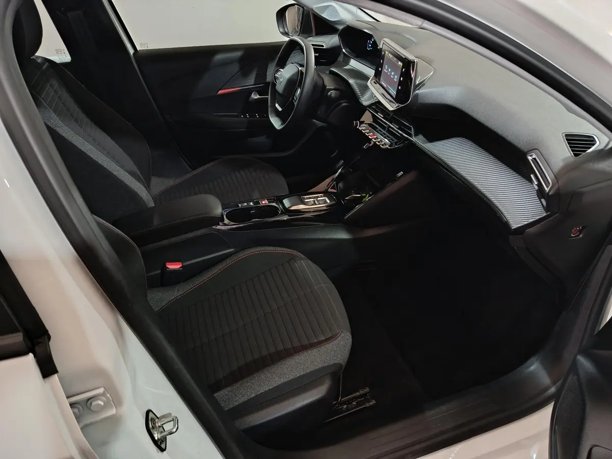 Intérieur de la Peugeot 208 électrique blanc, vue côté conducteur, tableau de bord moderne avec écran tactile central.