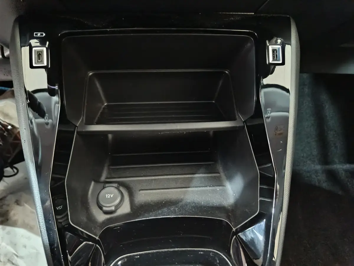 Vue rapprochée de la console centrale noire du Peugeot 208 électrique 2023 avec prises USB et prise 12V visible.