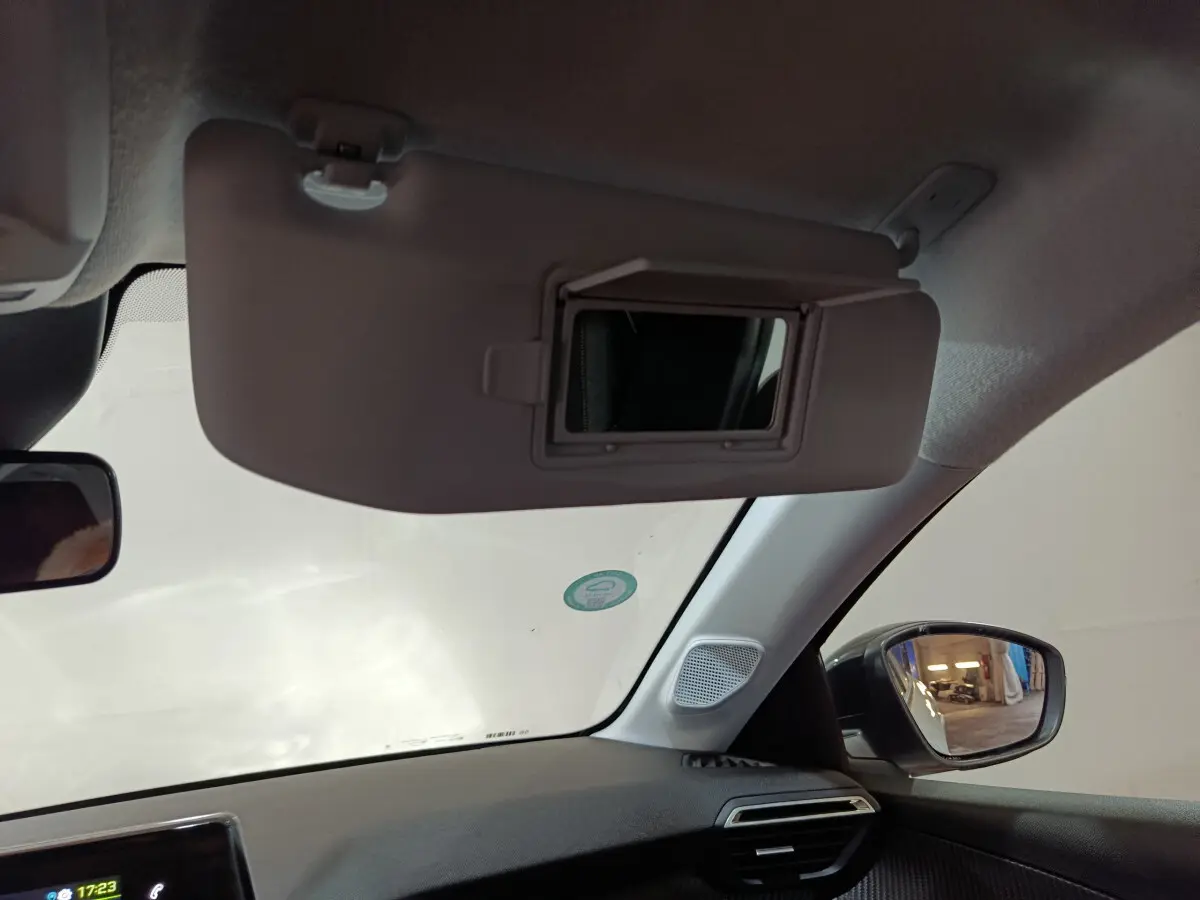 Intérieur du Peugeot 208 électrique blanc 2023, vue côté passager avec pare-soleil et miroir de courtoisie ouvert.