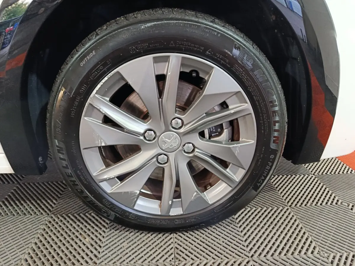 Gros plan sur la roue avant droite blanche d'une Peugeot 208 électrique 2023 avec jante alliage et pneu Michelin.