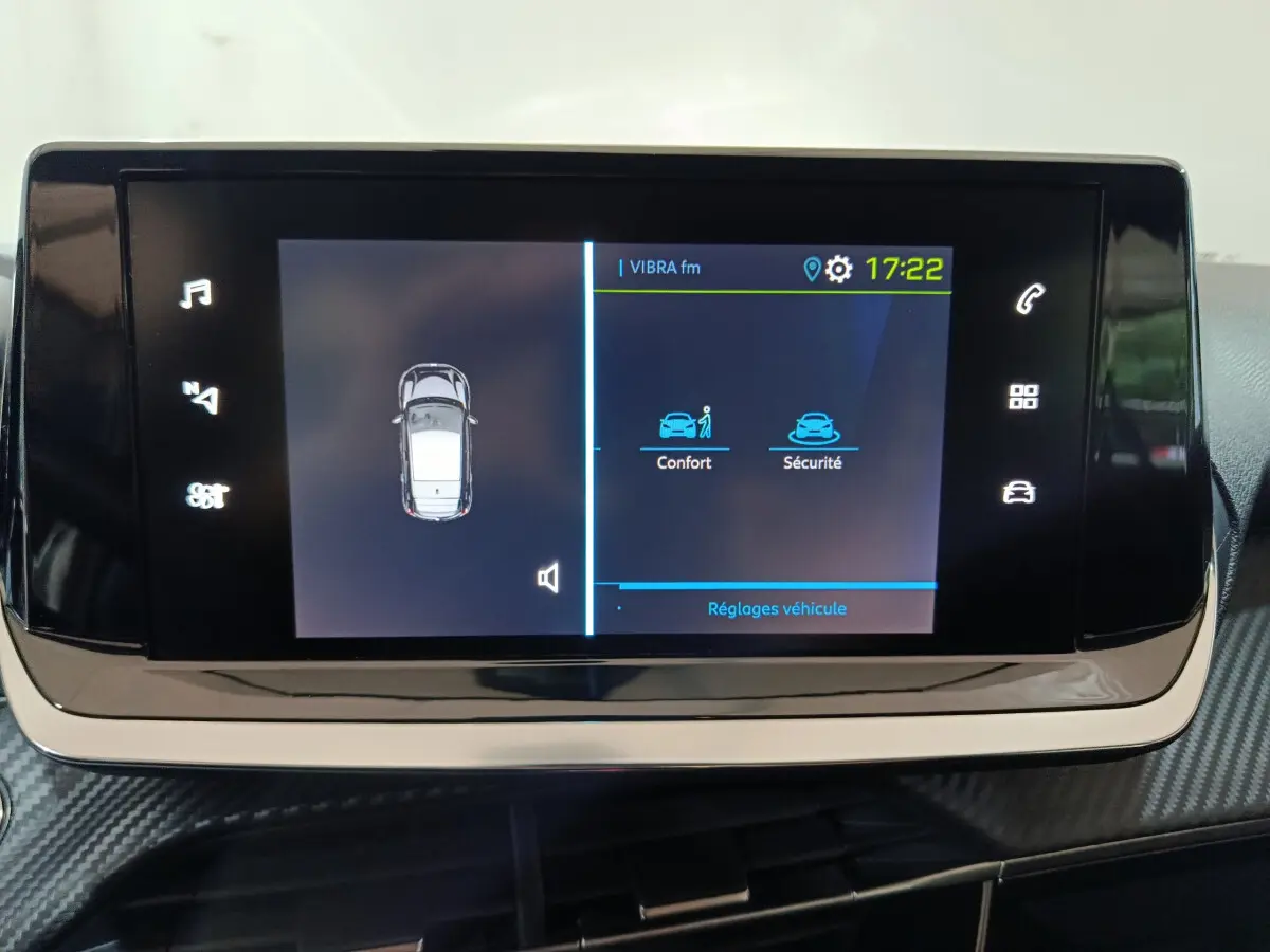Écran tactile central de la Peugeot 208 électrique blanche affichant les réglages confort et sécurité.