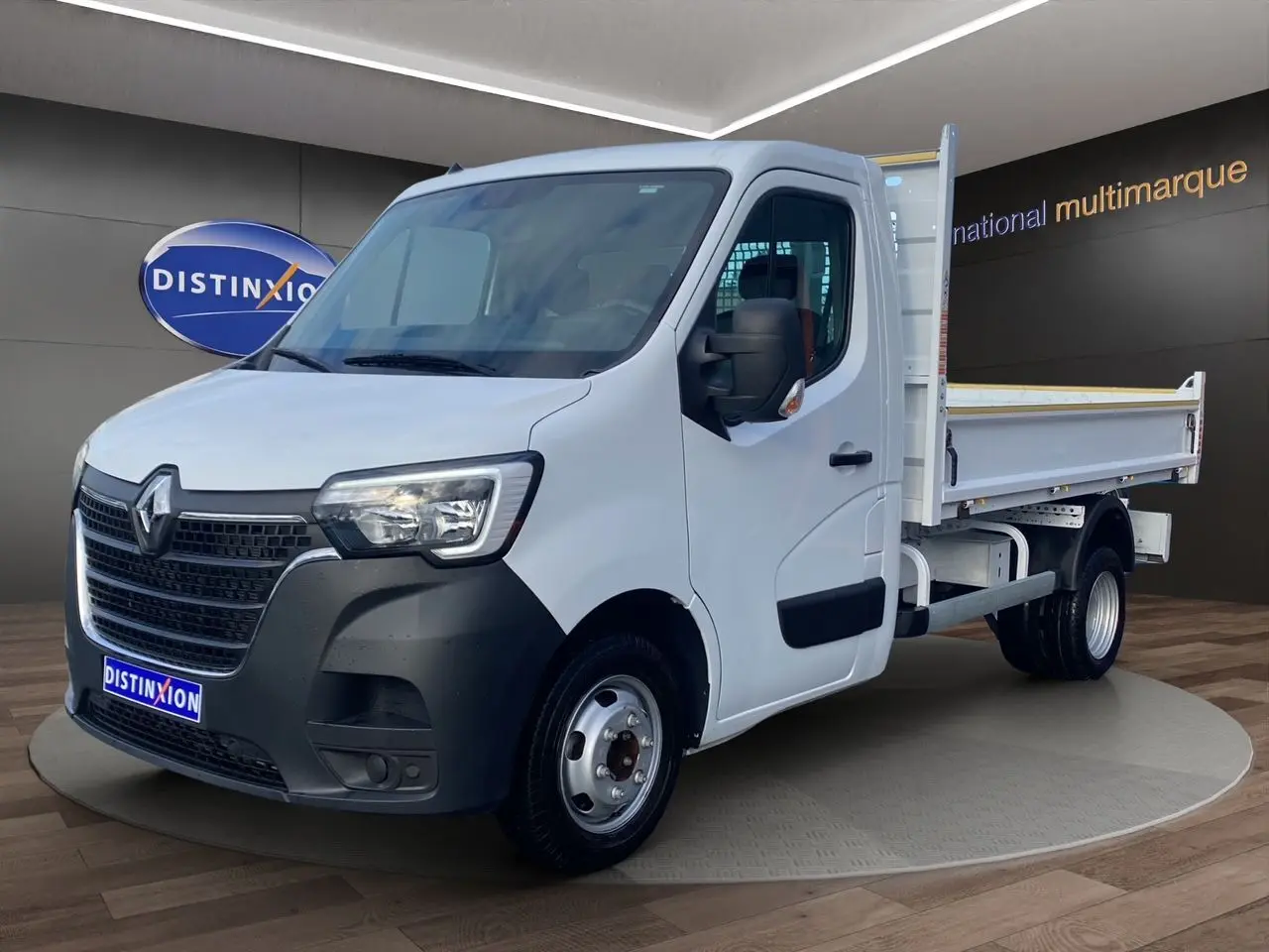 Renault Master blanc en vue 3/4 avant droit, benne arrière ouverte et pare-chocs avant noir mat.