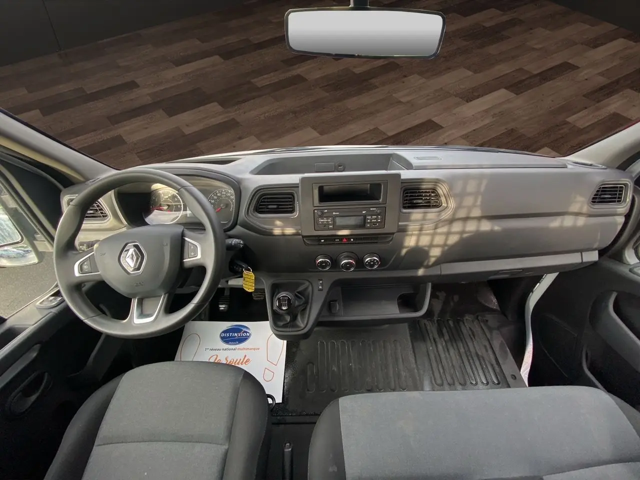 Vue intérieure avant du Renault Master 2024, tableau de bord noir avec volant multifonction et boîte manuelle.