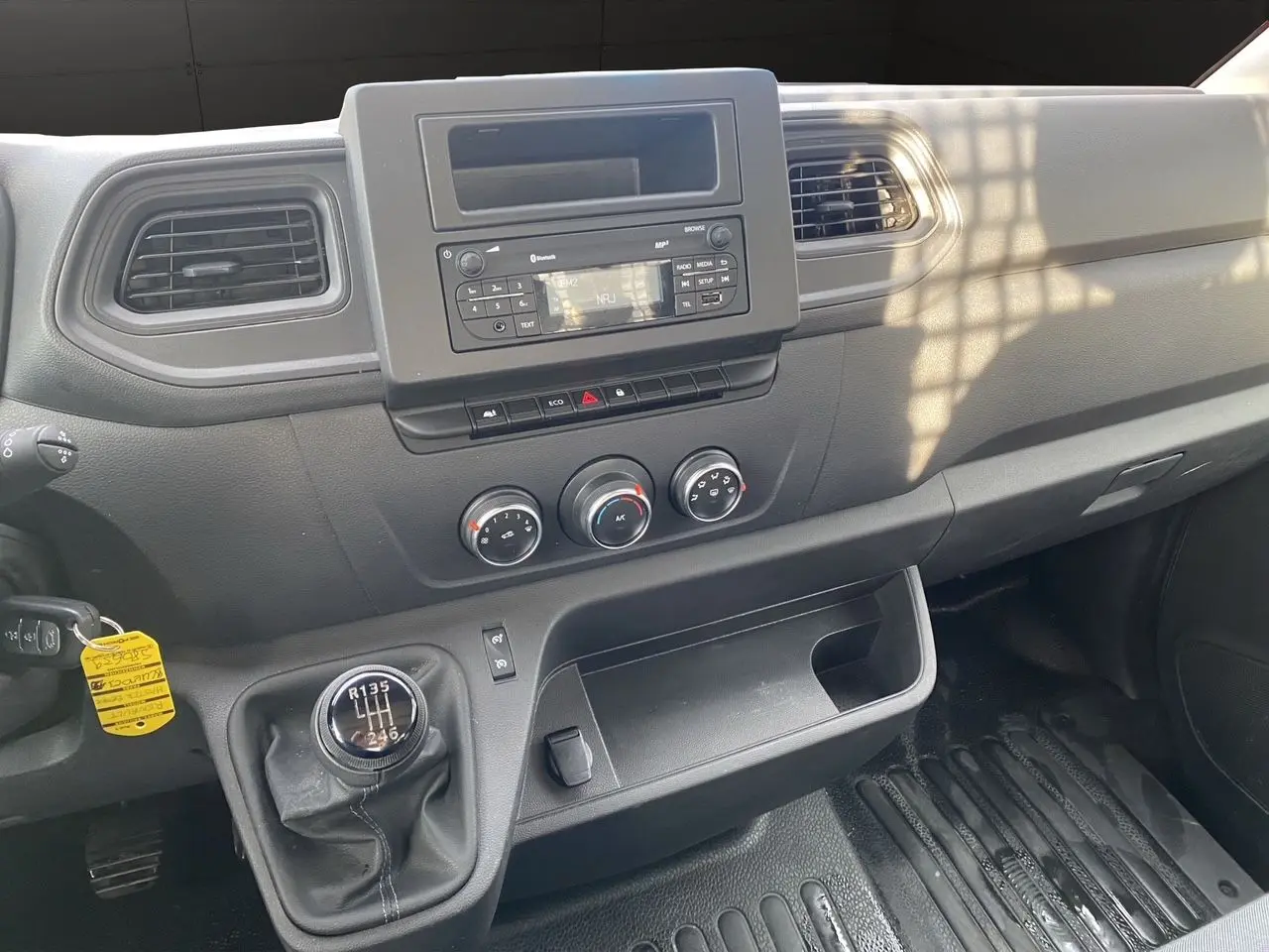 Vue intérieure du tableau de bord noir du Renault Master 2024, avec levier de vitesses manuel et commandes climatisation visibles.