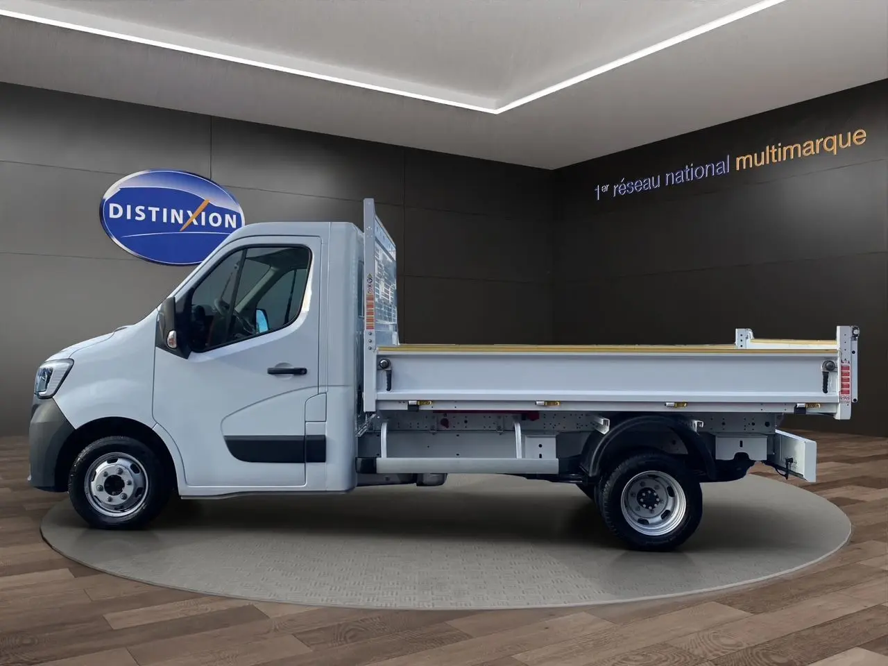 Renault Master blanc en vue profil côté gauche, benne arrière ouverte sur fond intérieur showroom.