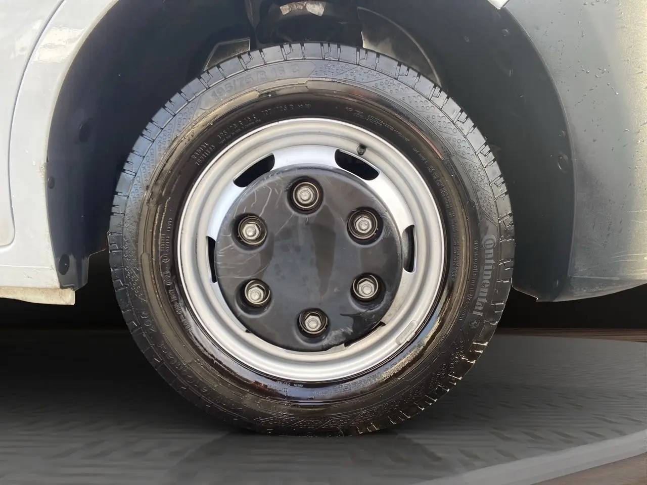 Gros plan sur la roue avant droite du Renault Master blanc 2024, avec jante acier et pneu Continental humide.