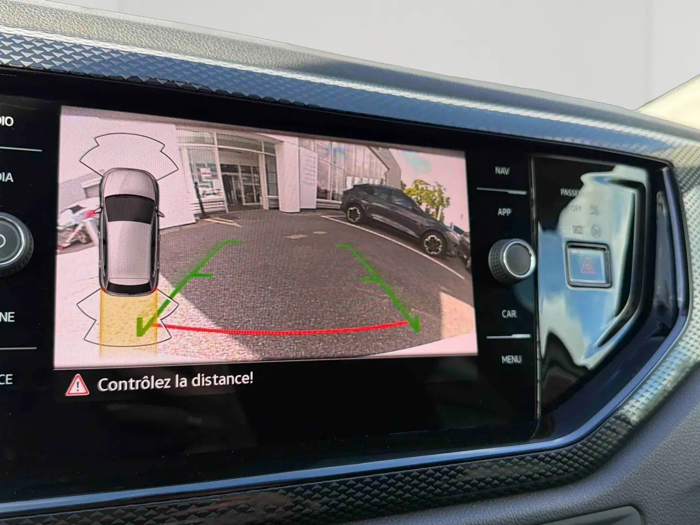 Écran tactile intérieur montrant la caméra de recul active avec vue arrière et guidage de trajectoire verte et rouge.