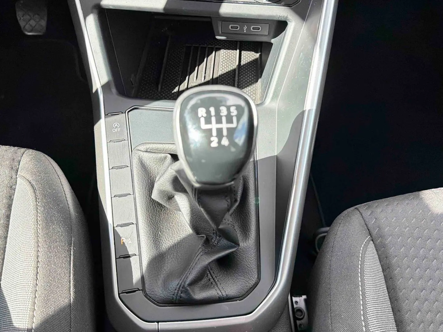 Vue plongeante sur la console centrale de la Volkswagen Polo blanche, mettant en valeur le levier de vitesse manuel noir.