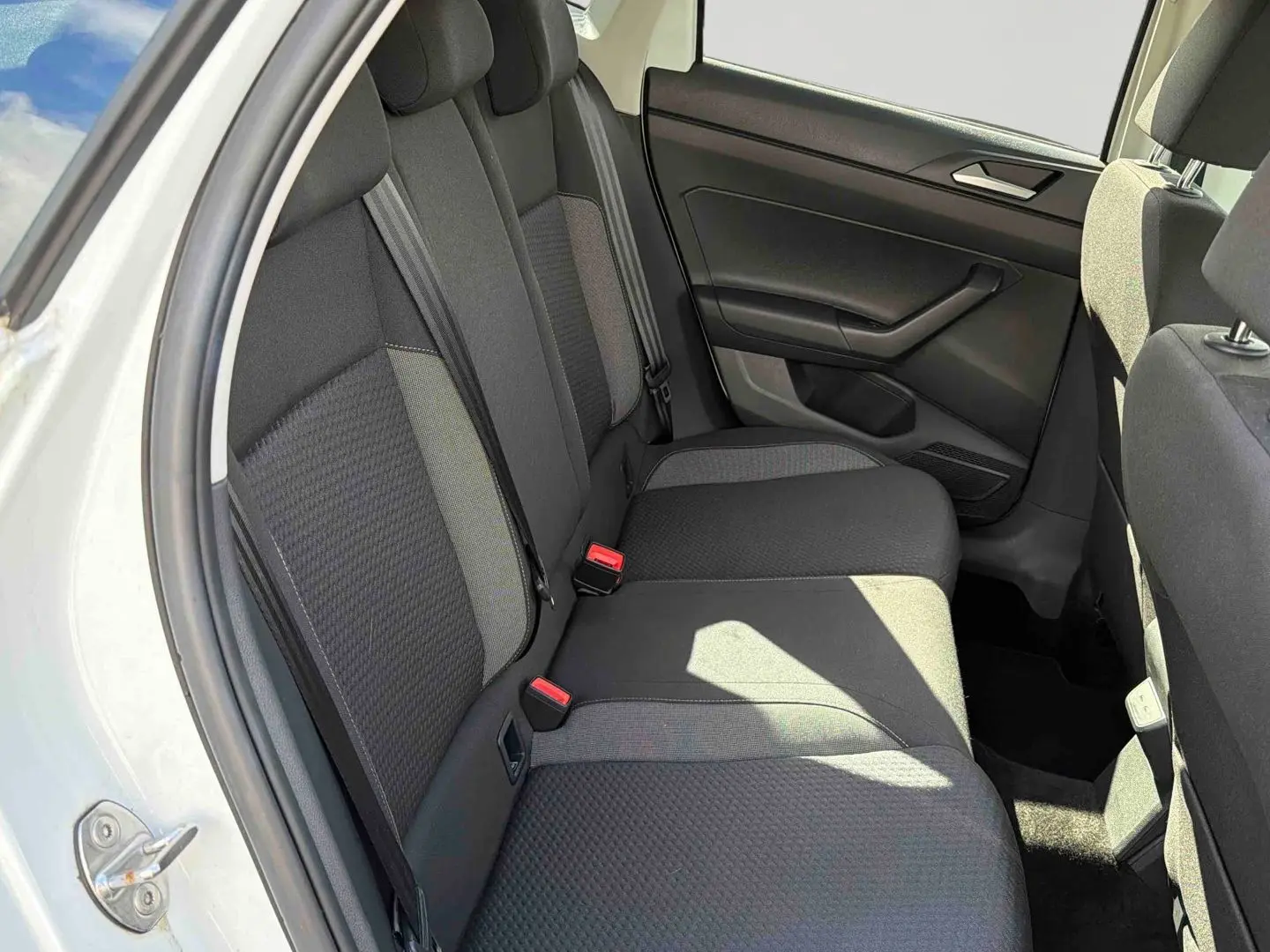 Vue intérieure côté arrière gauche montrant la banquette arrière grise d'une Volkswagen Polo blanche 2025.