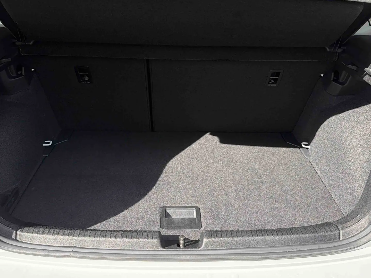 Coffre ouvert vu de face d'une Volkswagen Polo blanche, montrant un espace de chargement vide et propre.