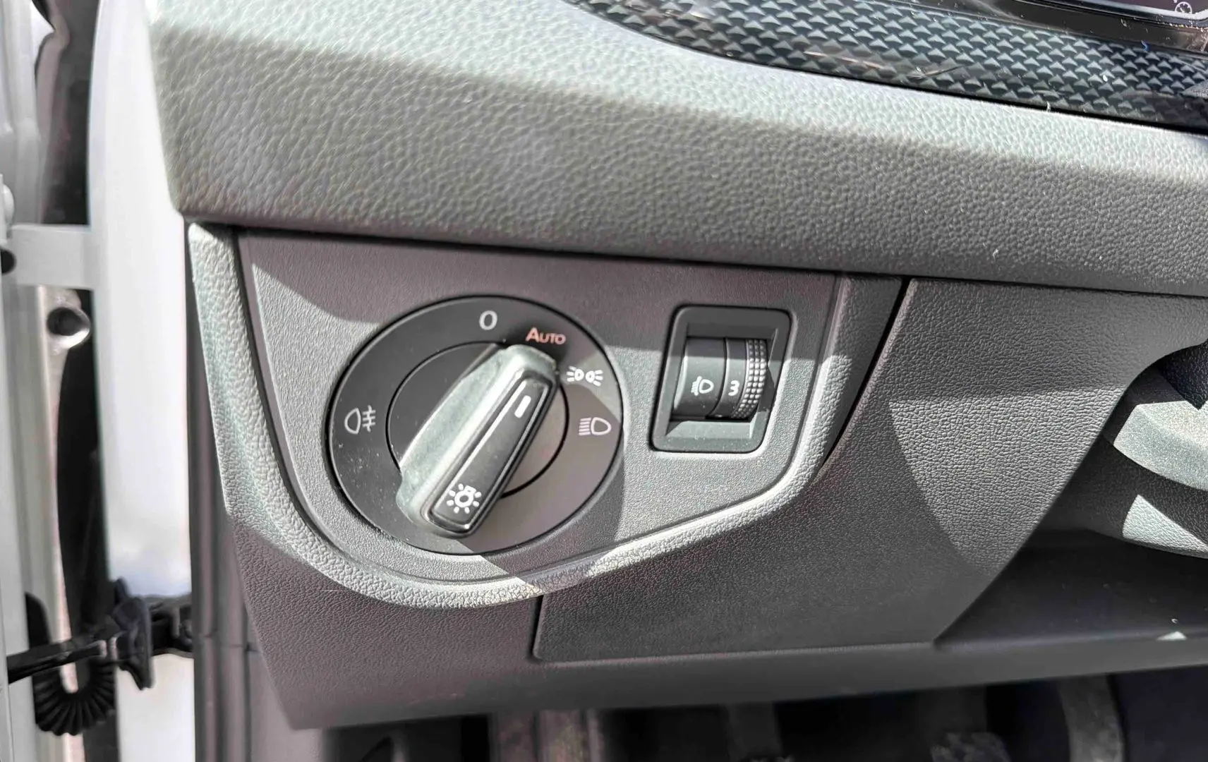 Détail du bouton de commande des feux sur le tableau de bord côté gauche d’une Volkswagen Polo blanche 2025.