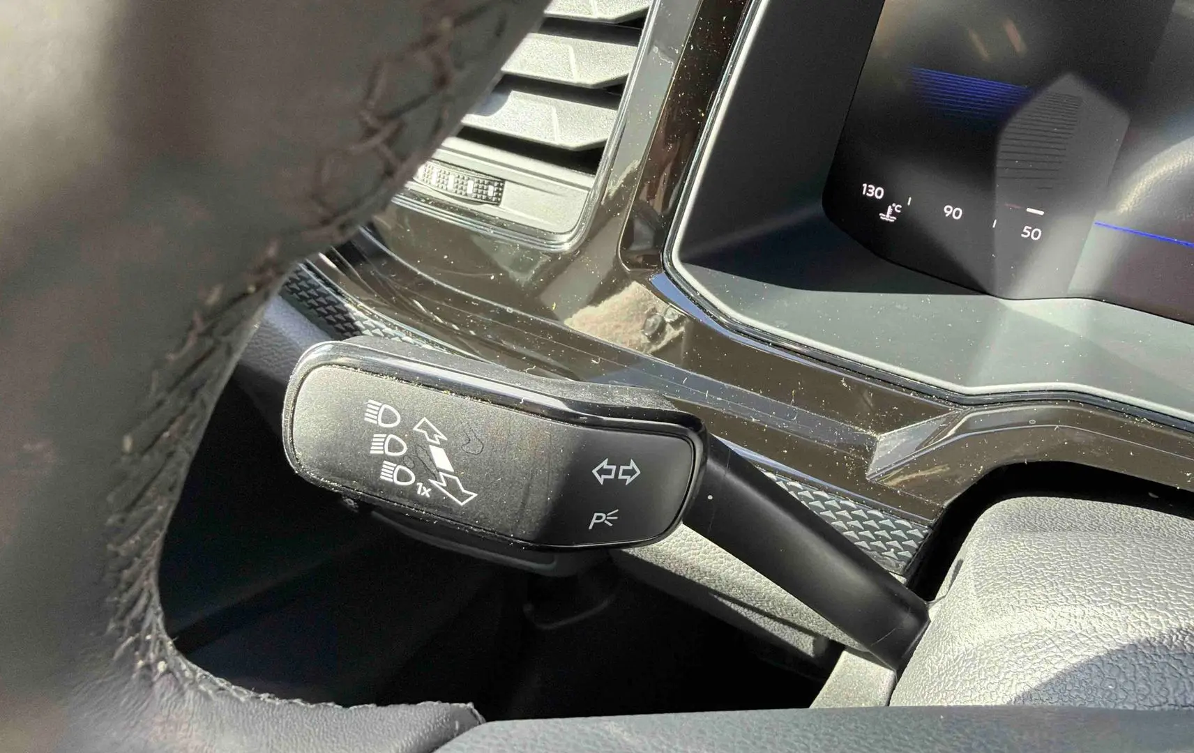 Gros plan sur la manette de clignotants à gauche du volant dans l’habitacle d’une Volkswagen Polo blanche.