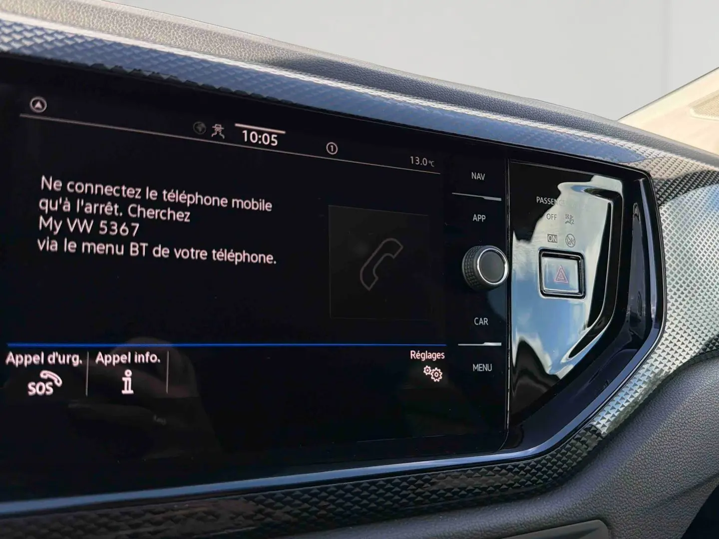 Vue rapprochée de l'écran tactile central et de la console noire brillante du tableau de bord de la Volkswagen Polo blanche.