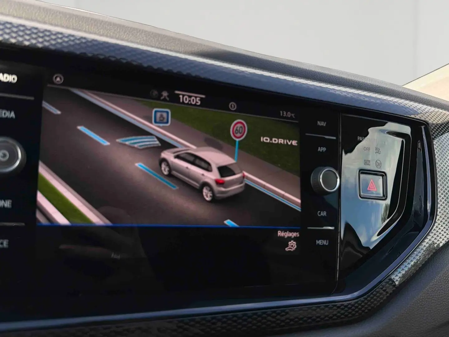 Écran tactile intérieur montrant la simulation d’une Volkswagen Polo blanche en conduite assistée sur route.