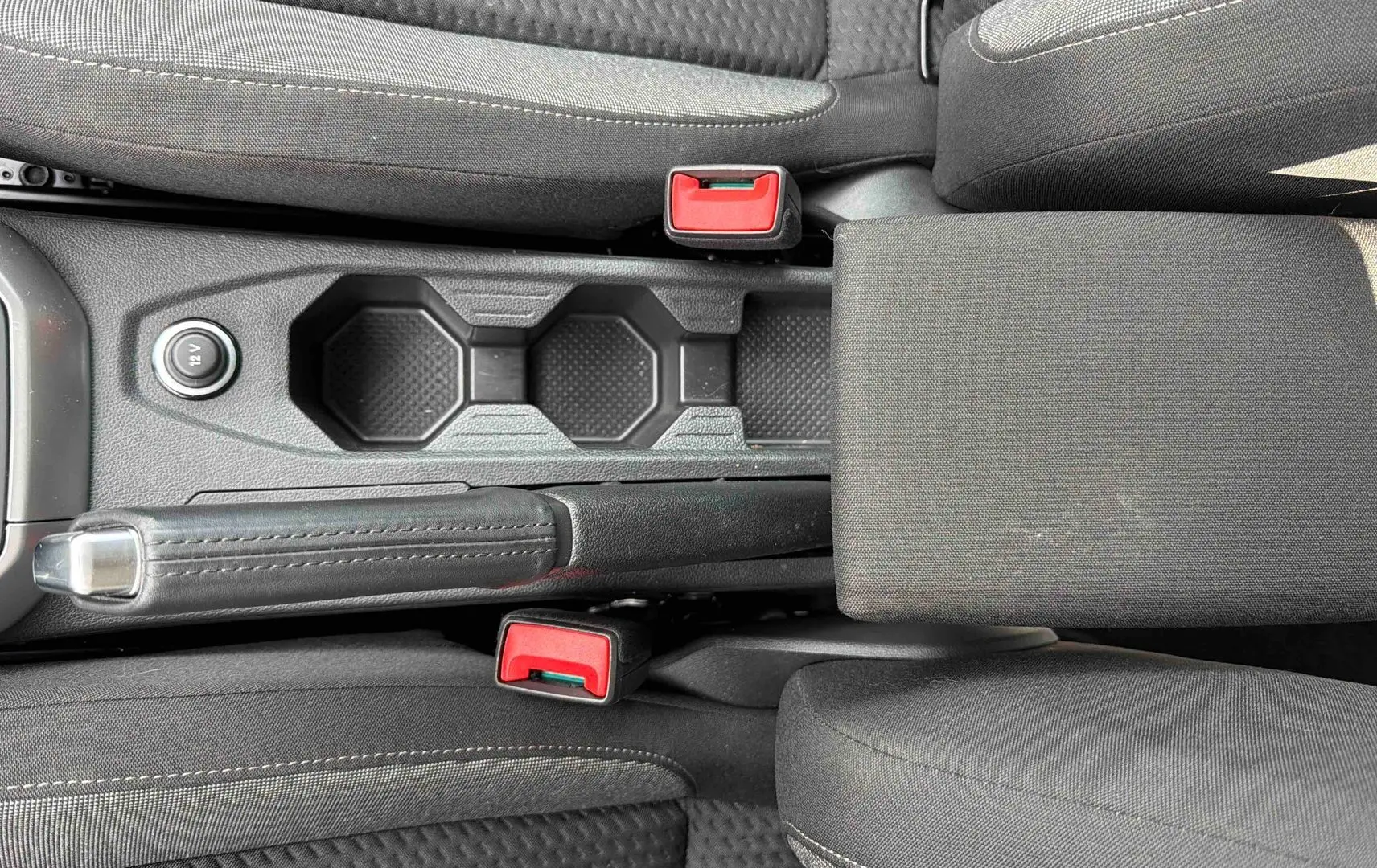 Vue plongeante sur la console centrale noire de la Volkswagen Polo 2025 avec frein à main et porte-gobelets.