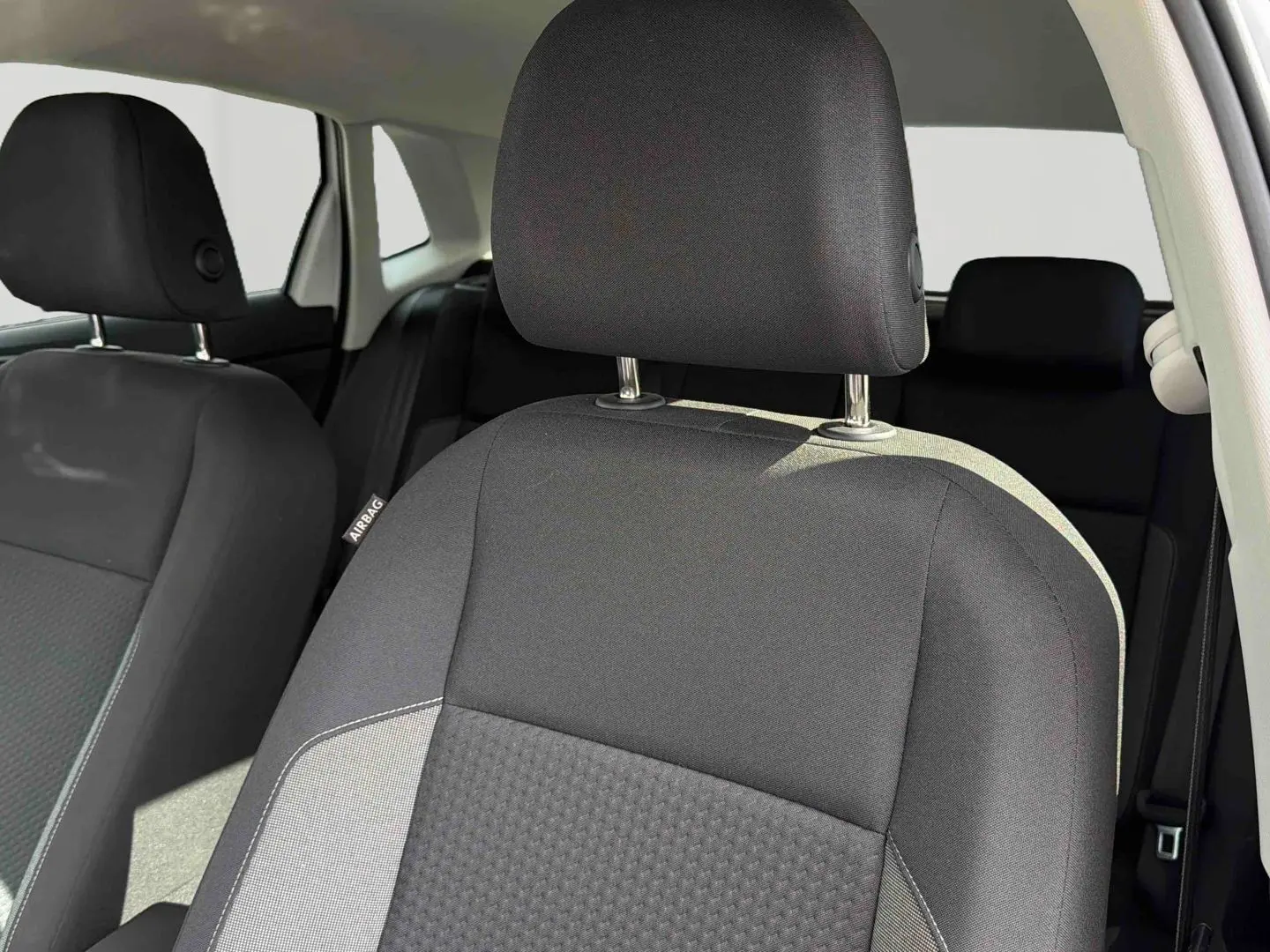 Gros plan sur le siège avant droit noir de la Volkswagen Polo 2025, intérieur tissu avec étiquette airbag visible.