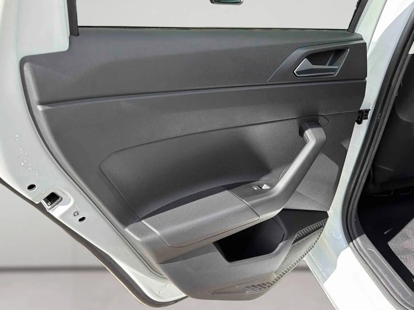 Vue rapprochée de la porte arrière gauche blanche d'une Volkswagen Polo 2025 avec garniture intérieure noire et commandes de vitre.