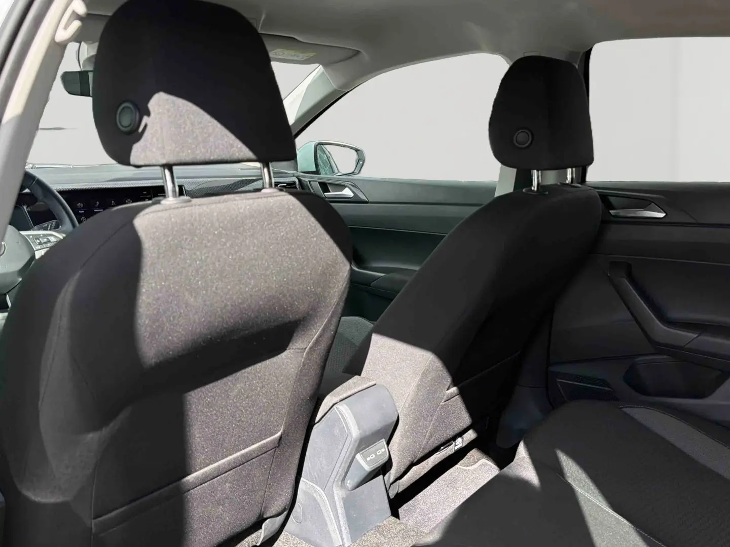 Vue intérieure arrière montrant les sièges avant noirs et la console centrale d'une Volkswagen Polo blanche 2025.