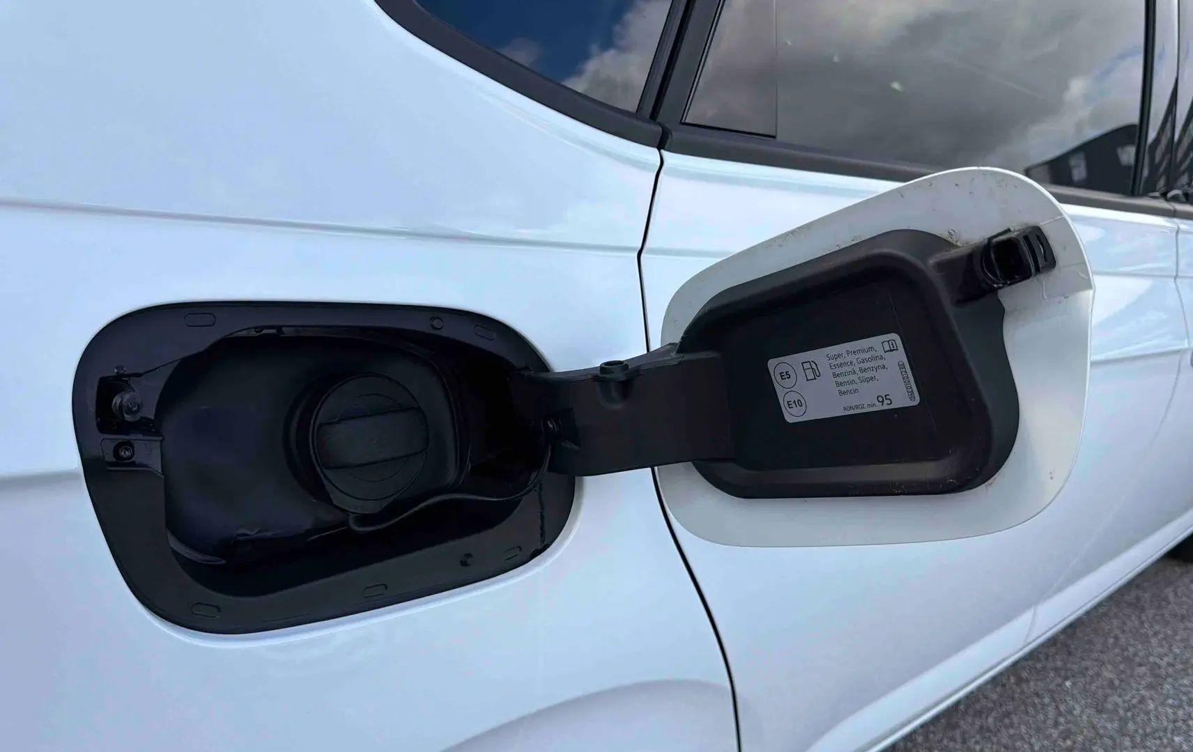 Gros plan sur la trappe à carburant ouverte côté gauche d'une Volkswagen Polo blanche essence 2025.