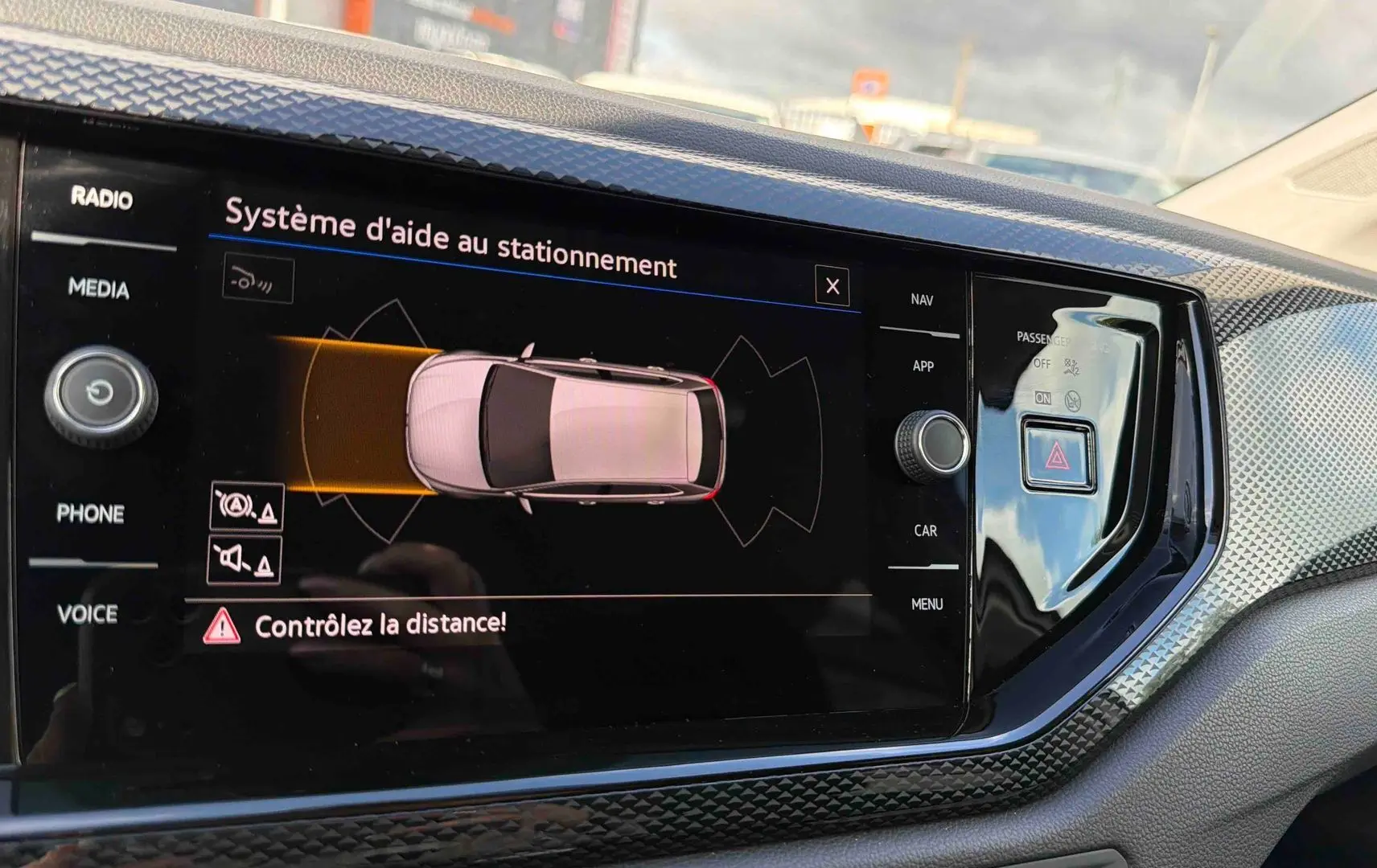 Écran tactile intérieur montrant le système d'aide au stationnement de la Volkswagen Polo blanche, vue de face.