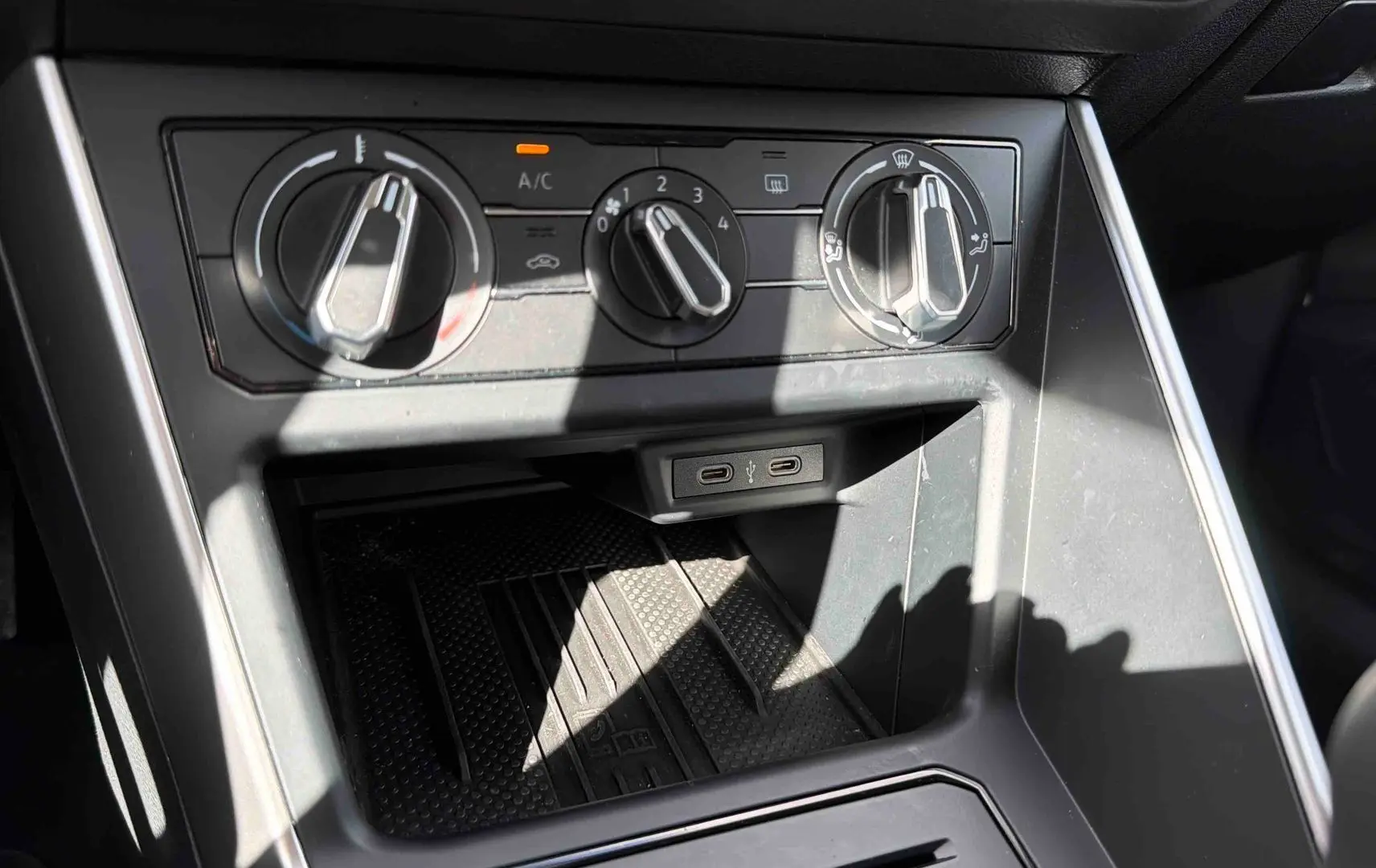 Gros plan sur les commandes de climatisation et les ports USB-C du tableau de bord d’une Volkswagen Polo blanche.