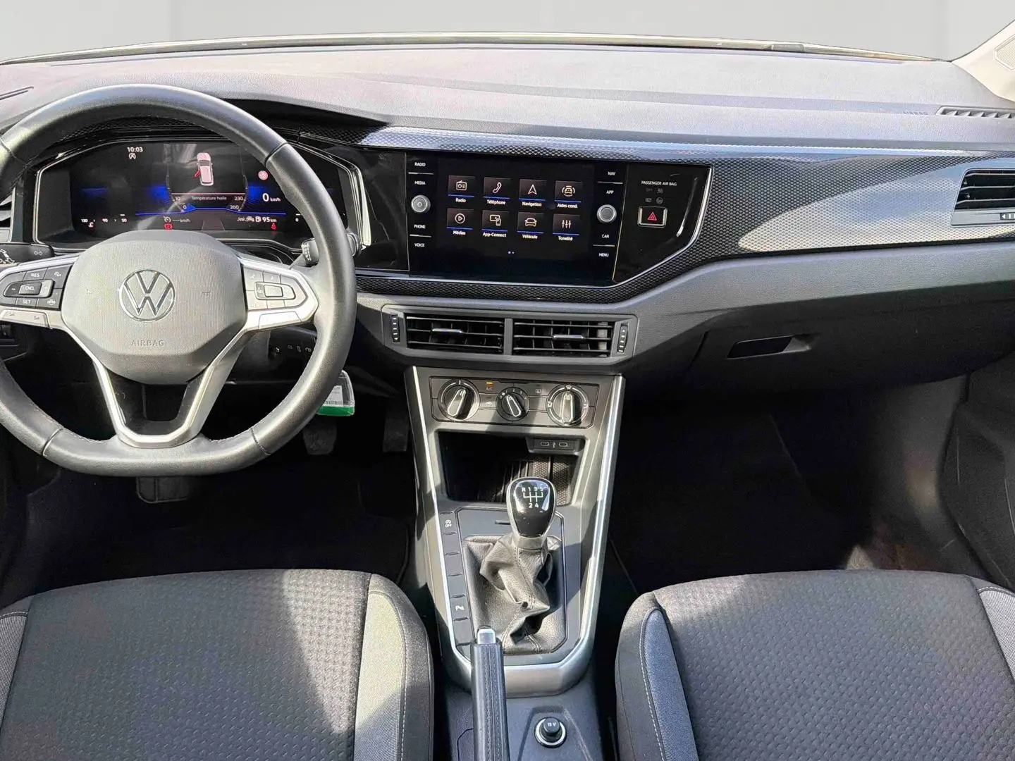Vue intérieure avant de la Volkswagen Polo 2025, montrant le volant cuir, écran tactile et levier de vitesses manuel.