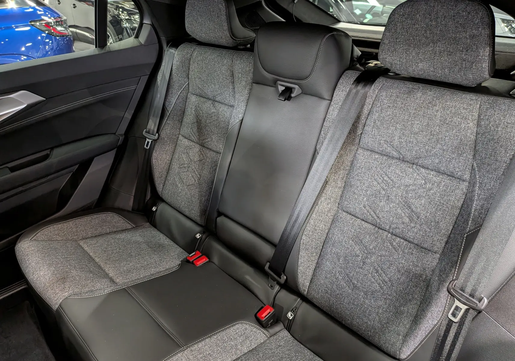 Vue intérieure sur la banquette arrière du Renault Rafale 2026, tissu gris et cuir noir avec ceintures de sécurité visibles.