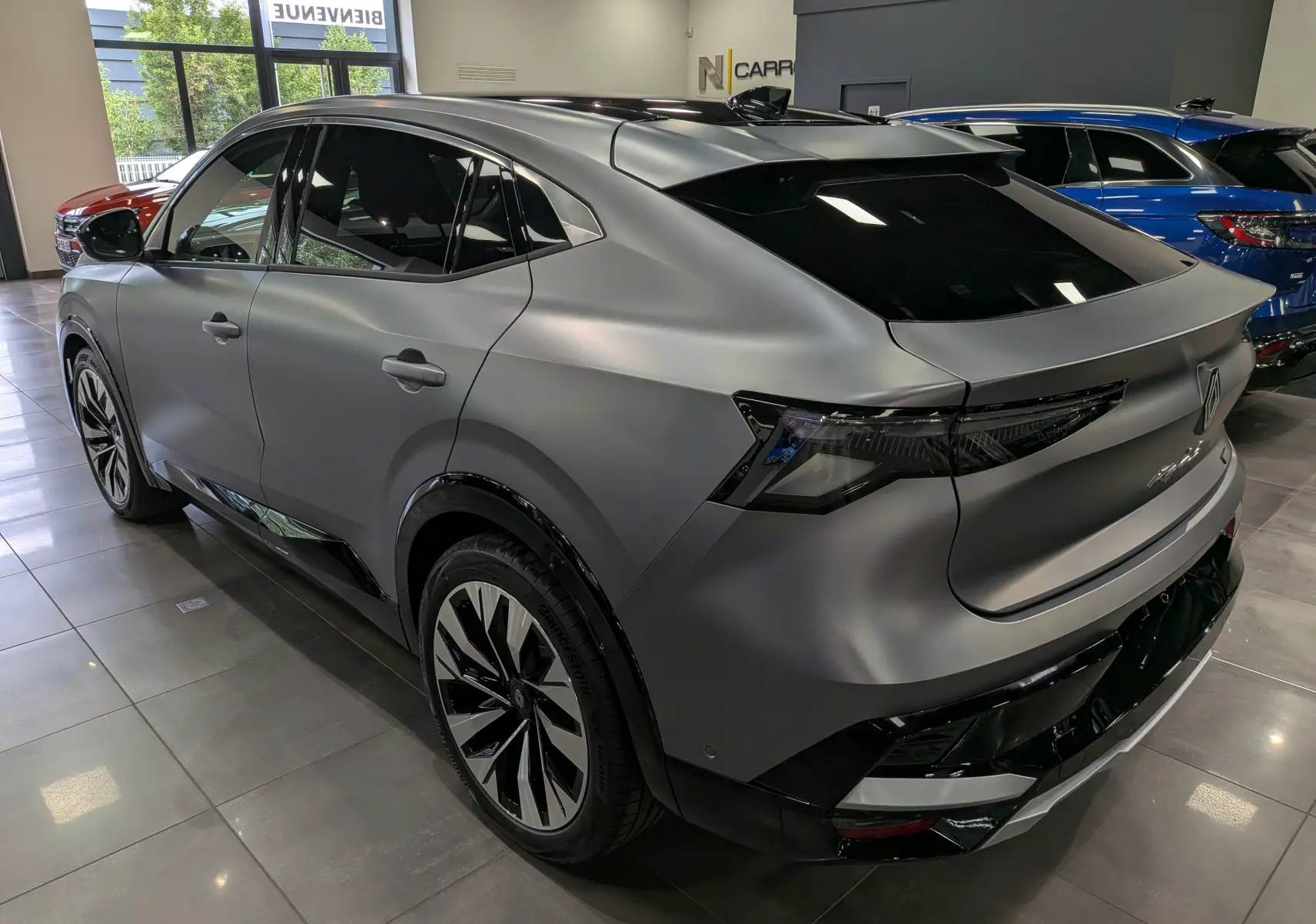 Vue 3/4 arrière droite du Renault Rafale gris schiste satin avec jantes bicolores et vitres teintées en showroom.
