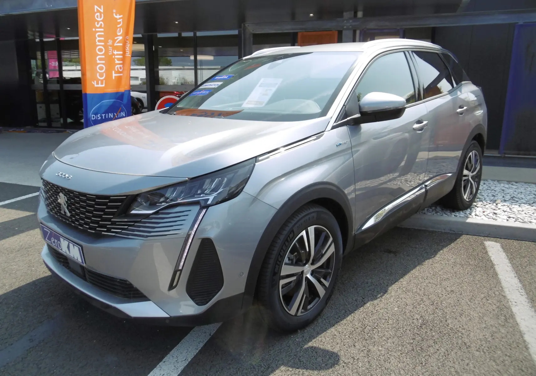 Peugeot 3008 Hybrid gris Artense en 3/4 avant droit, avec calandre noire et jantes alliage bicolores.