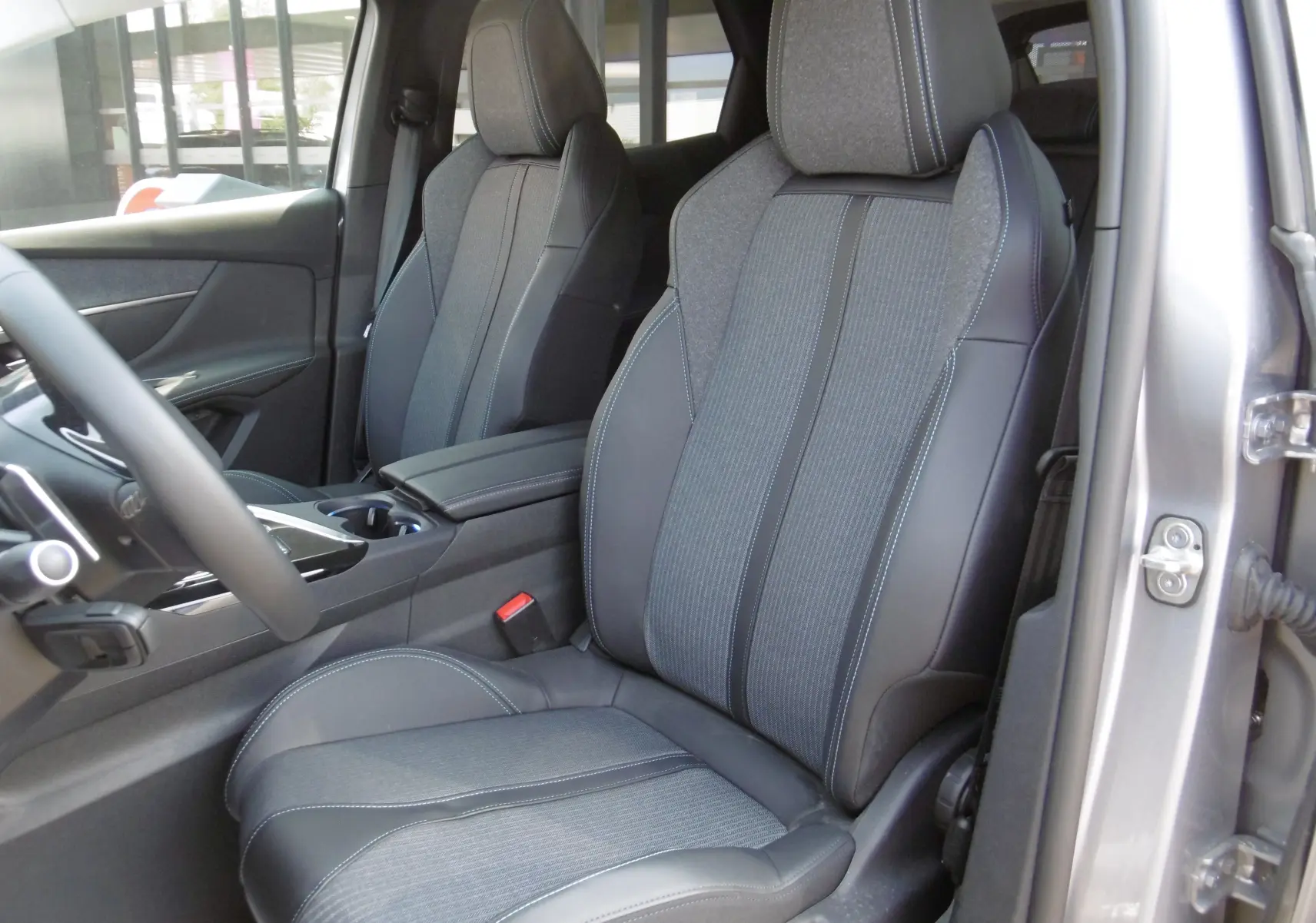 Vue intérieure côté droit du Peugeot 3008 Hybrid 225ch avec sièges en cuir et tissu gris, volant partiellement visible.