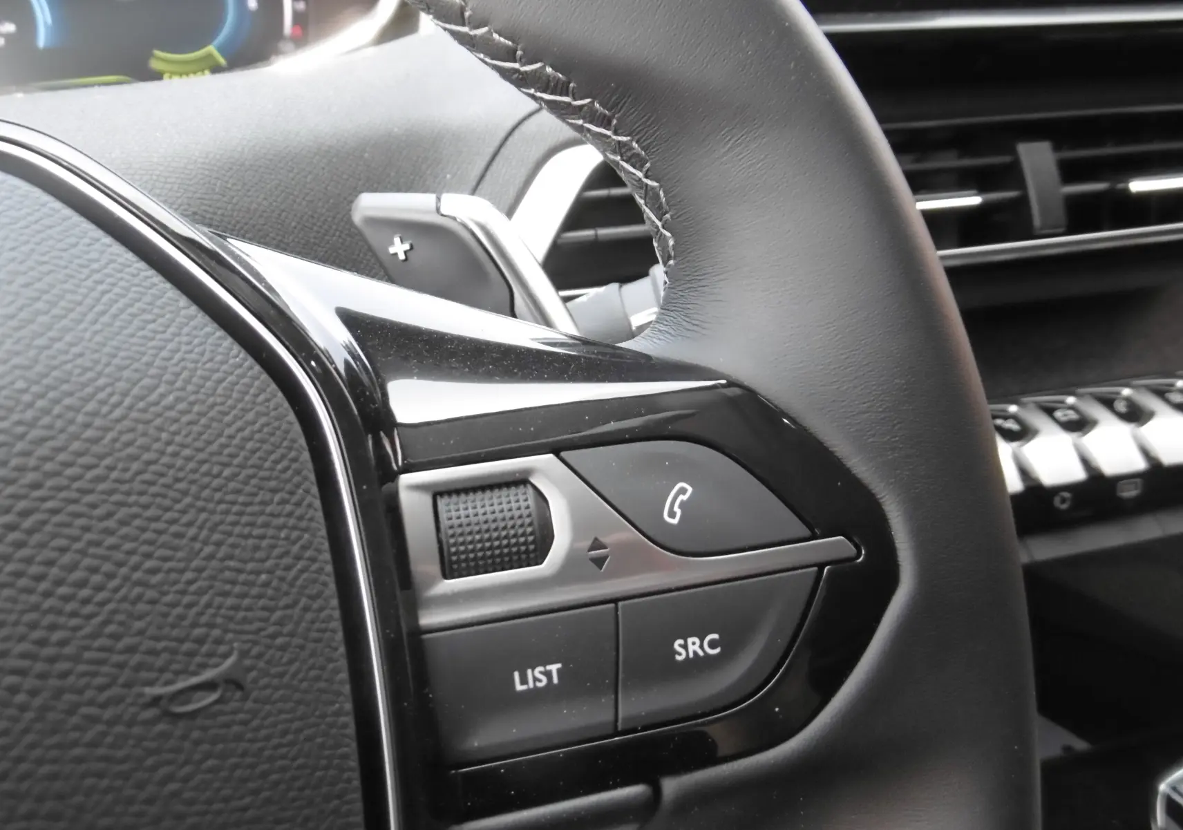 Gros plan sur la partie gauche du volant noir du Peugeot 3008 Hybrid 225ch, montrant les commandes audio et téléphone.