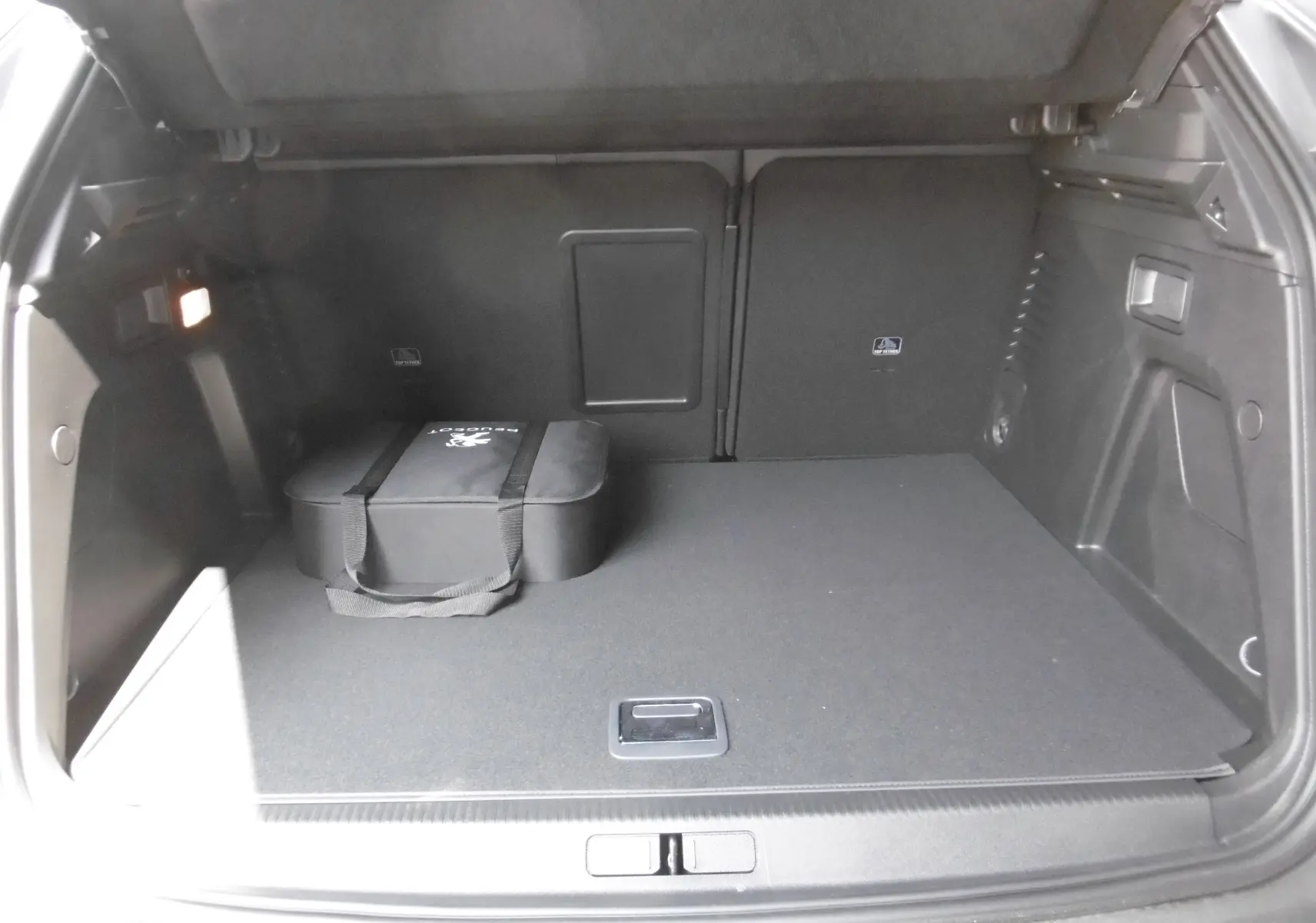 Coffre ouvert du Peugeot 3008 gris Artense, vue arrière montrant un sac noir de rangement posé à gauche.