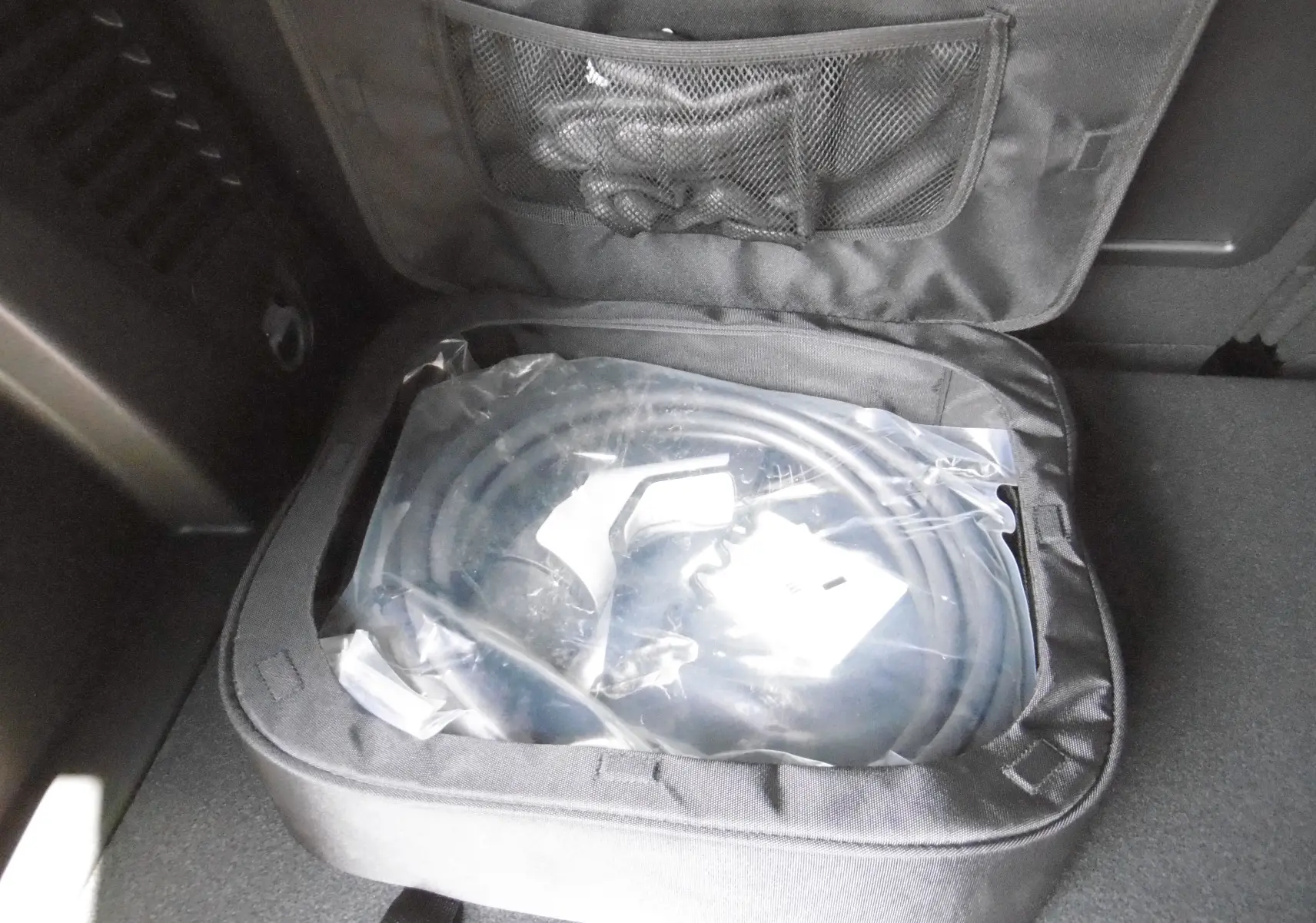 Chargeur de câble hybride dans le coffre d'un Peugeot 3008 gris Artense, vue rapprochée du rangement intérieur.