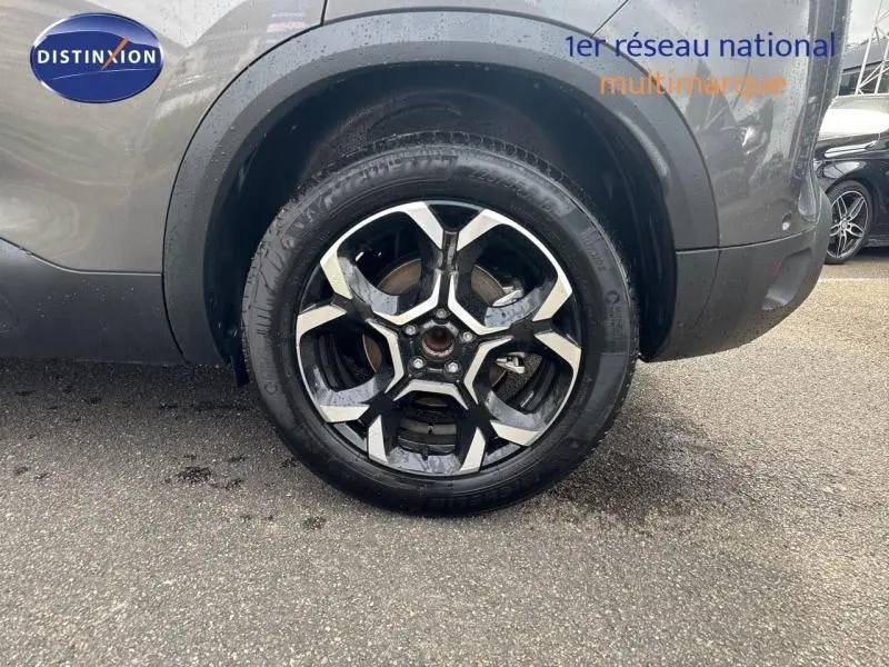 Gros plan sur la roue avant droite avec jante alu noire et argentée du Citroën C5 Aircross Gris Platinium.