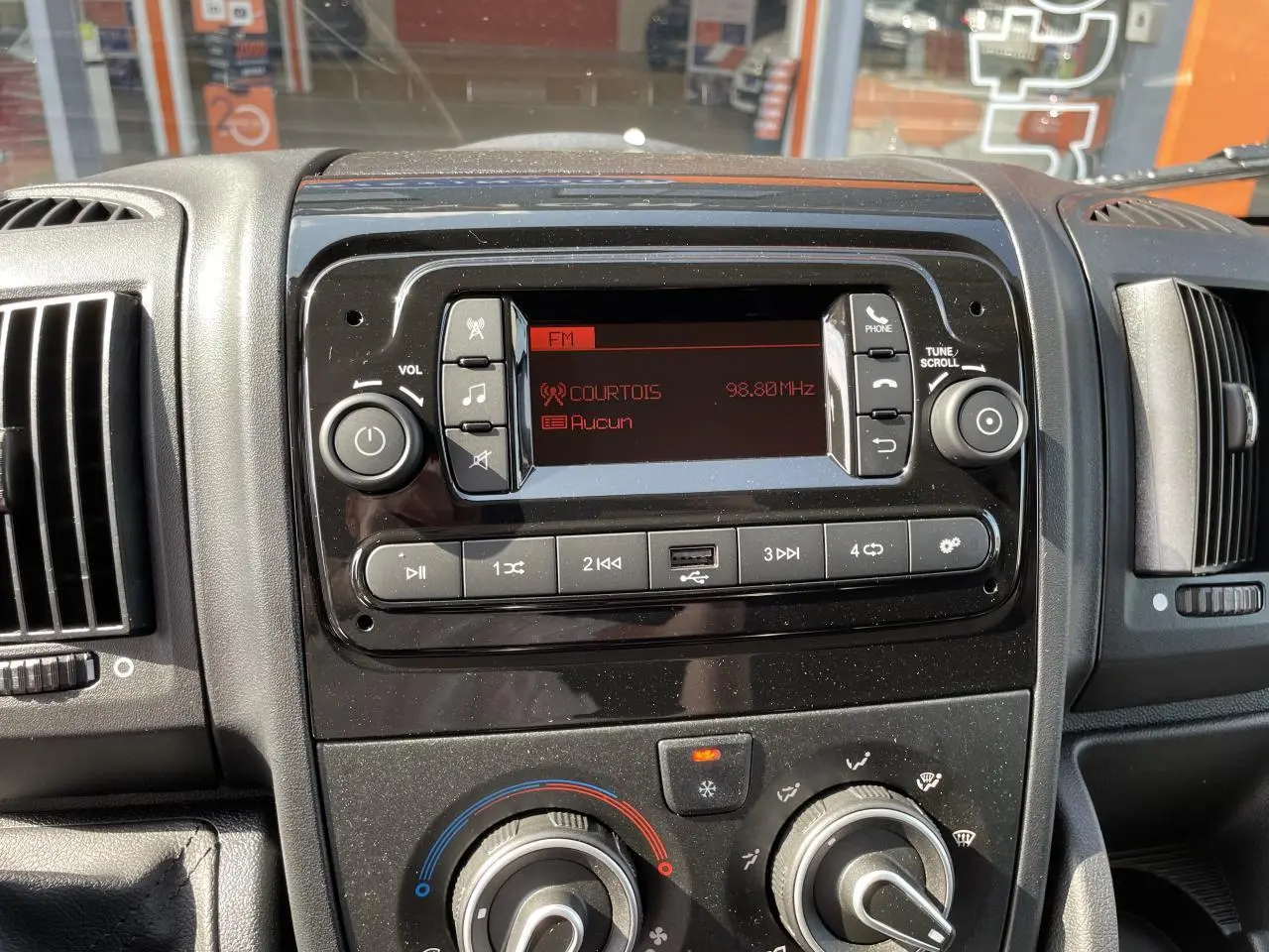 Vue rapprochée du tableau de bord du Peugeot Boxer Fourgon 2023, avec radio numérique et commandes de climatisation.
