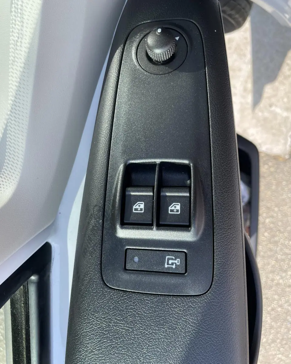 Gros plan sur les commandes de lève-vitres et réglage des rétroviseurs côté conducteur du Peugeot Boxer blanc 2023.