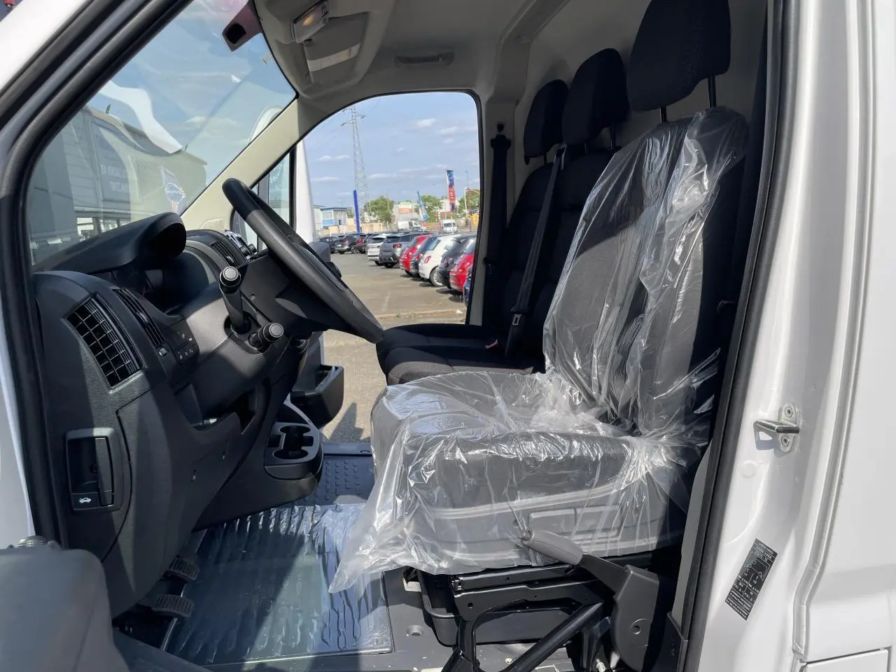 Vue intérieure côté conducteur du Peugeot Boxer Fourgon blanc 2023, sièges avant protégés par film plastique.