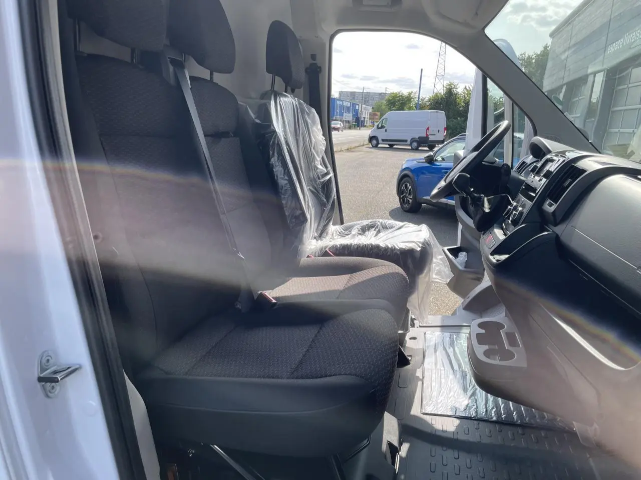 Vue intérieure côté conducteur du Peugeot Boxer Fourgon blanc 2023, montrant les sièges avant et le tableau de bord.