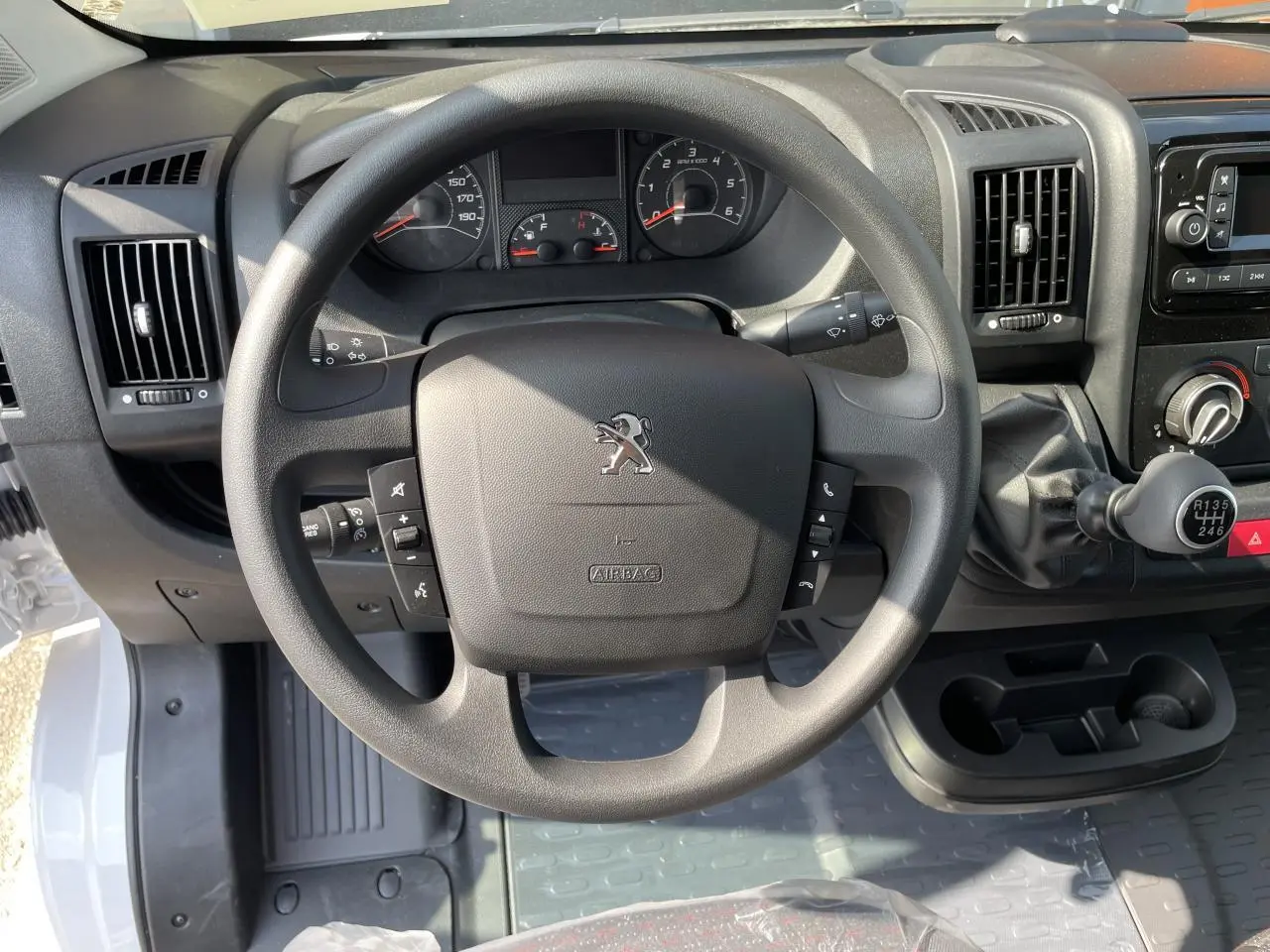 Vue rapprochée du volant Peugeot Boxer Fourgon blanc 2023 avec tableau de bord et levier de vitesses manuel.