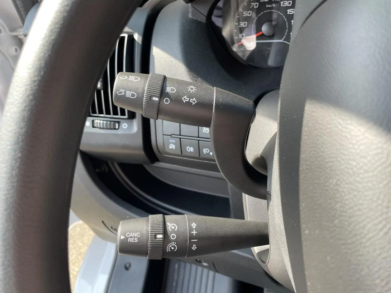Gros plan sur les commandes de clignotants et régulateur de vitesse du Peugeot Boxer Fourgon blanc, côté gauche du volant.