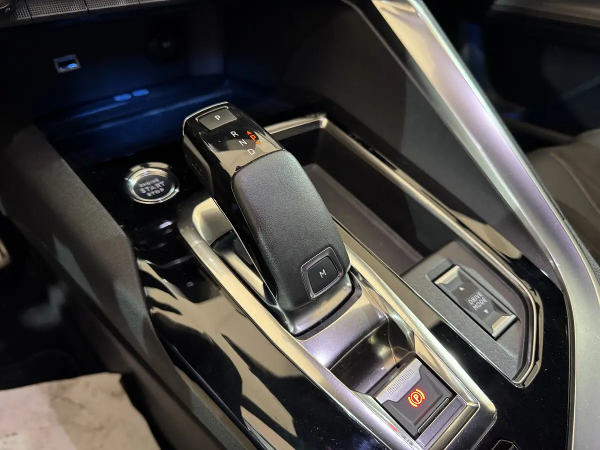 Gros plan sur la console centrale du Peugeot 3008 gris clair, montrant le levier de vitesse automatique et le bouton start/stop.