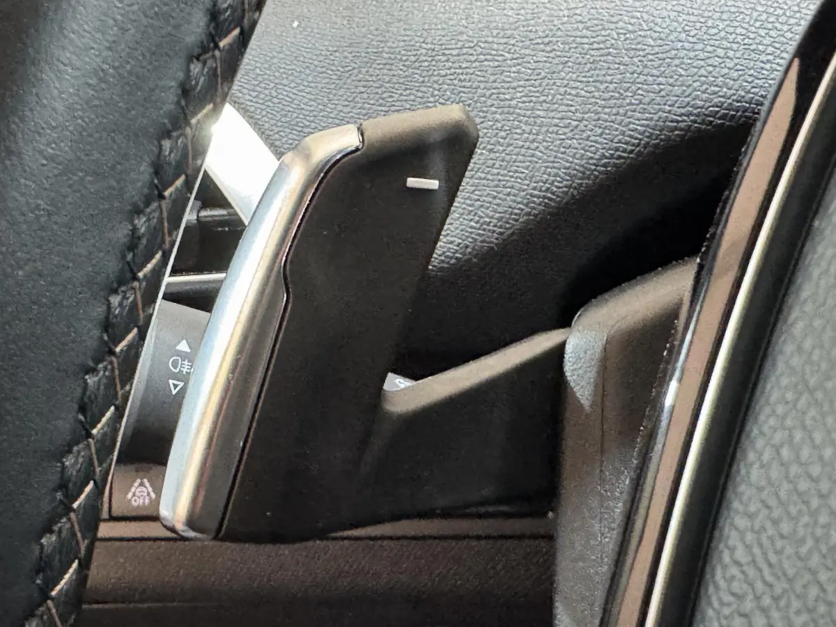 Gros plan sur la palette de changement de vitesses côté gauche du volant cuir noir du Peugeot 3008 gris clair.