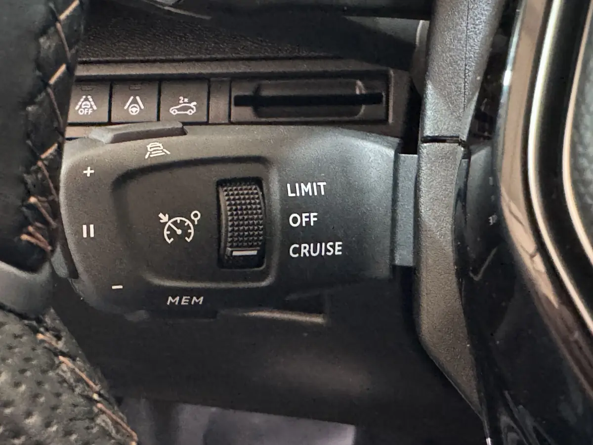 Gros plan sur la commande de régulateur de vitesse et limiteur, intérieur noir du Peugeot 3008 gris clair.