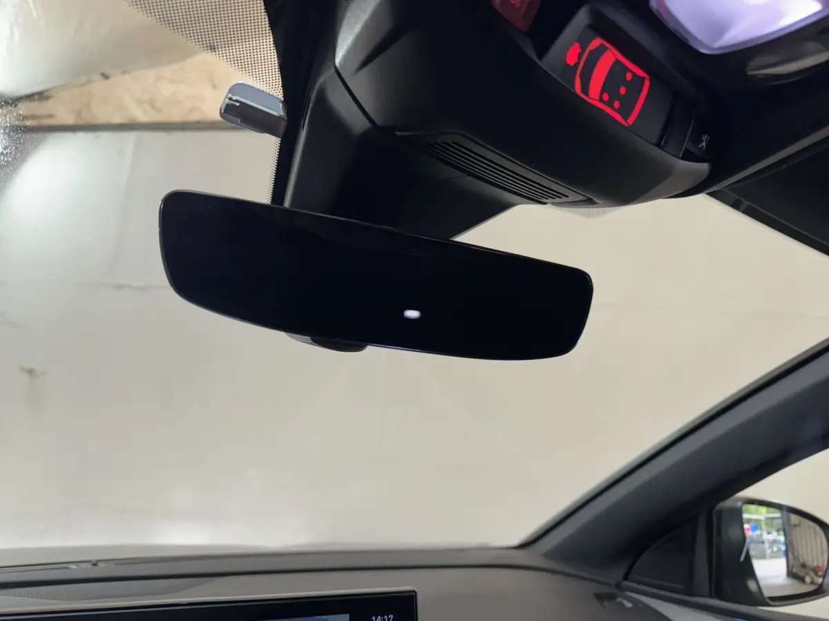 Vue intérieure du rétroviseur central noir et du plafonnier avec témoin rouge dans un Peugeot 3008 gris clair.