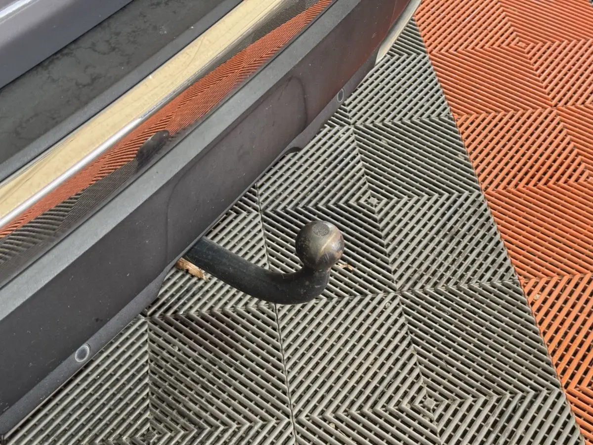 Gros plan sur l'attelage de remorque arrière d'un Peugeot 3008 gris clair, avec capteurs de stationnement visibles.