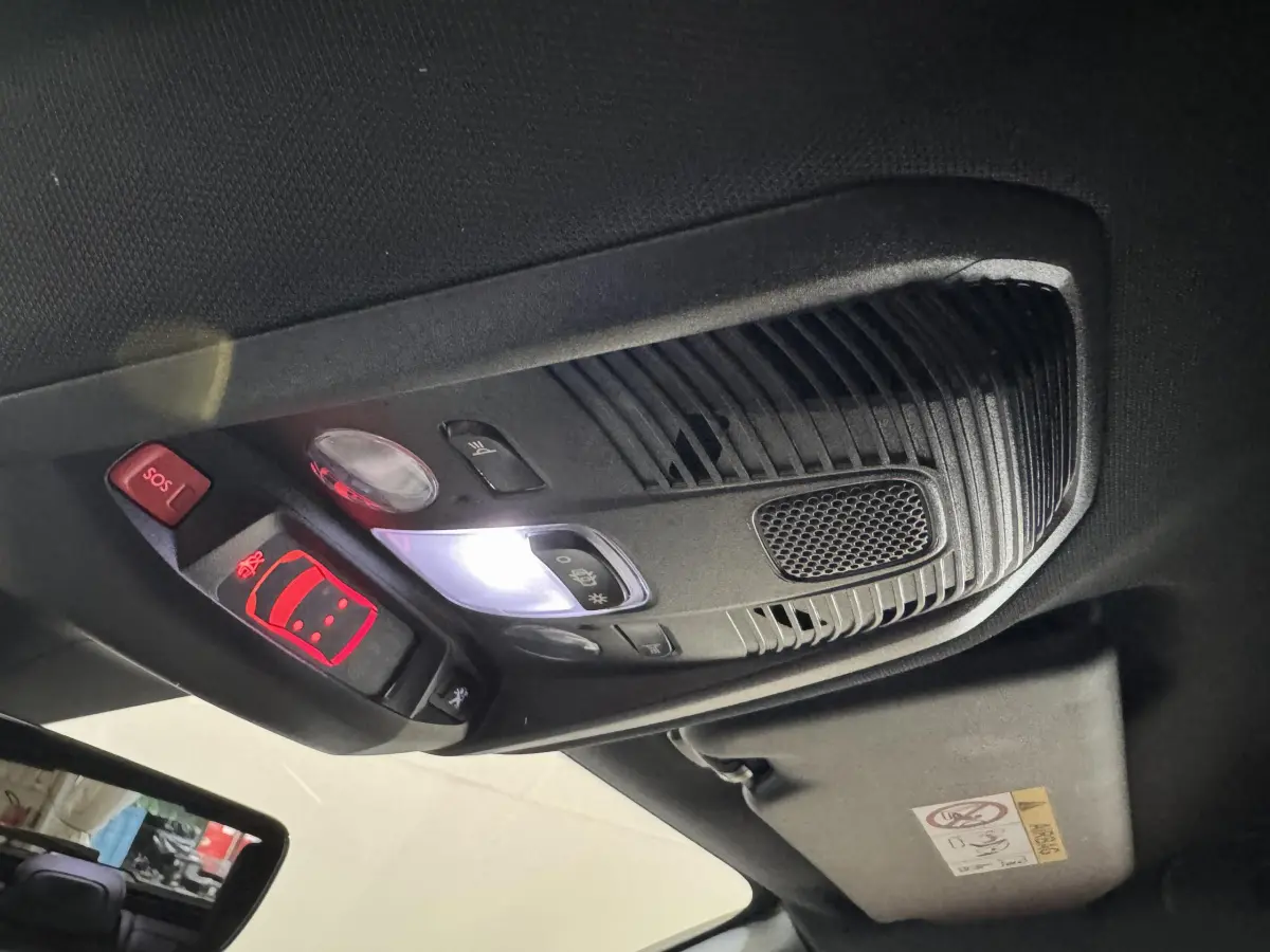 Vue intérieure en gros plan du plafonnier noir avec boutons SOS et éclairage du Peugeot 3008 gris clair 2021.