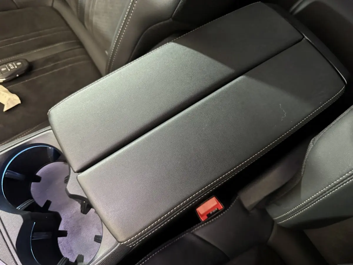 Vue rapprochée de l'accoudoir central en cuir noir avec surpiqûres blanches dans l'habitacle du Peugeot 3008 gris clair.