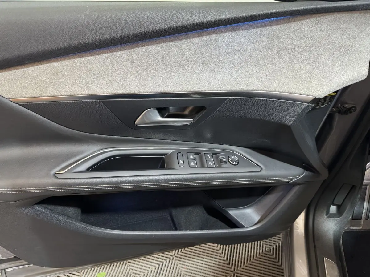 Vue intérieure côté conducteur de la porte du Peugeot 3008 GT gris clair avec commandes vitres et rétroviseurs.