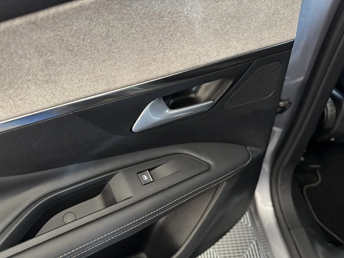 Gros plan sur la porte avant gauche gris clair du Peugeot 3008 avec poignée argentée et bouton de verrouillage.